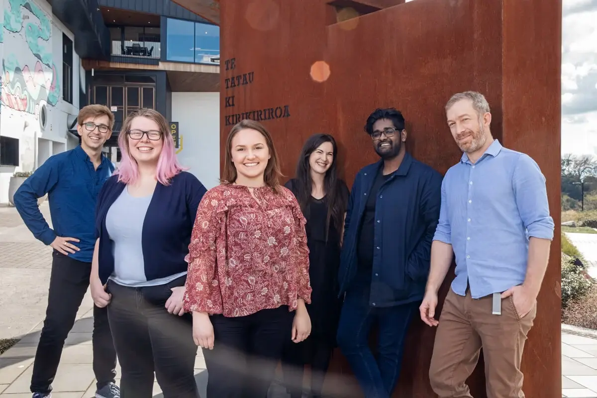 An image of a group of people standing in front of a brown statue.